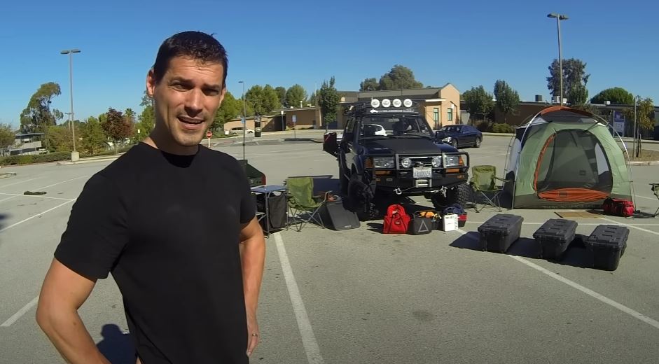 Michael stands in front of his truck with his camping gear.