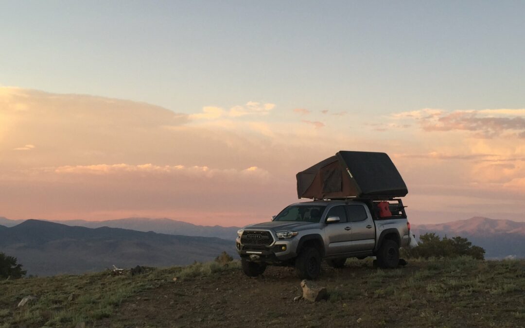 An offroad truck sits on a hillside at sunset.