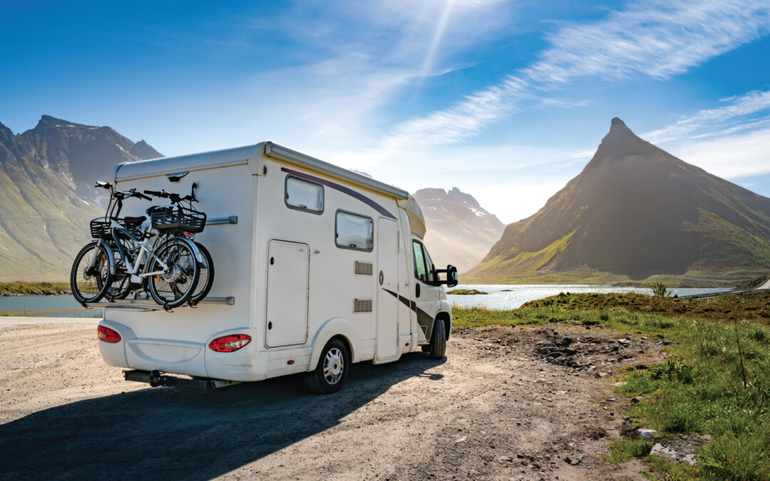 A small RV sits overlooking a mountain.